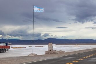Vista panorámica de las salinas argentinas con una bandera nacional, símbolo del potencial minero del país impulsado por el litio, el cobre y el oro.