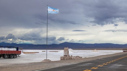 Vista panorámica de las salinas argentinas con una bandera nacional, símbolo del potencial minero del país impulsado por el litio, el cobre y el oro.