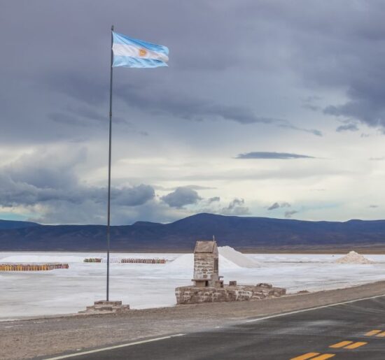 Vista panorámica de las salinas argentinas con una bandera nacional, símbolo del potencial minero del país impulsado por el litio, el cobre y el oro.