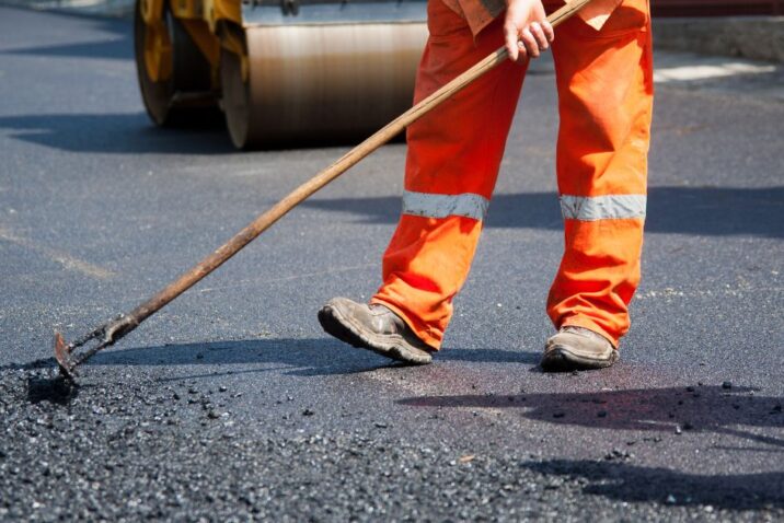 Operario trabajando en la imprimación y pavimentación de la Ruta Provincial 43. La obra, clave para la logística del litio, requiere especificaciones técnicas de alta resistencia para soportar el tránsito pesado y las amplitudes térmicas extremas de Antofagasta de la Sierra.