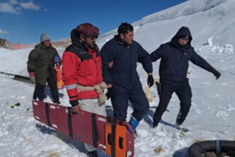 Rescatistas y trabajadores trasladan una camilla en la nieve durante el operativo por los mineros varados en la Puna, en el caso del accidente de Rio Tinto.