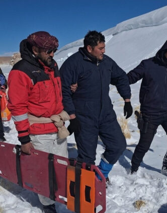 Rescatistas y trabajadores trasladan una camilla en la nieve durante el operativo por los mineros varados en la Puna, en el caso del accidente de Rio Tinto.