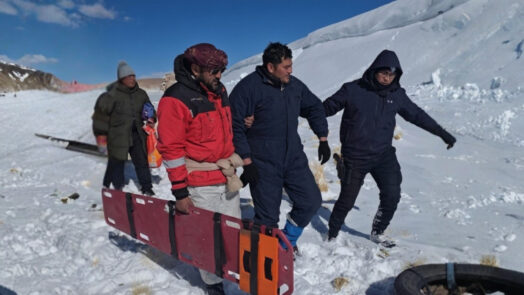 Rescatistas y trabajadores trasladan una camilla en la nieve durante el operativo por los mineros varados en la Puna, en el caso del accidente de Rio Tinto.