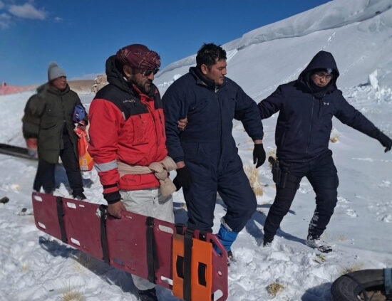 Rescatistas y trabajadores trasladan una camilla en la nieve durante el operativo por los mineros varados en la Puna, en el caso del accidente de Rio Tinto.