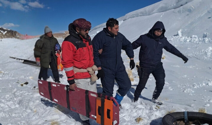 Rescatistas y trabajadores trasladan una camilla en la nieve durante el operativo por los mineros varados en la Puna, en el caso del accidente de Rio Tinto.