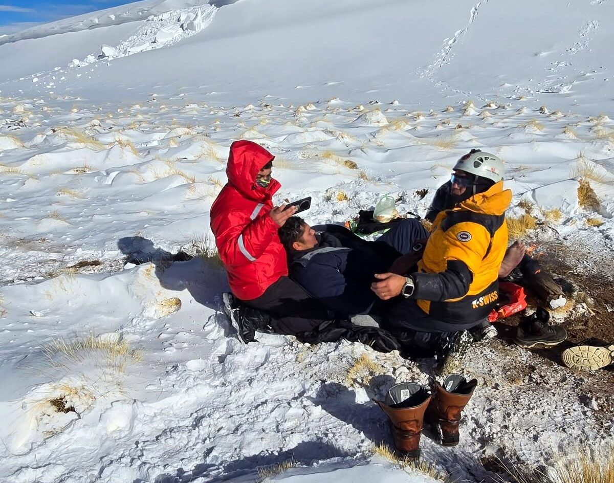 Rescatistas asisten a un trabajador sentado sobre la nieve en plena puna, durante el episodio de Río Tinto bajo investigación por el accidente de los mineros de Fénix.