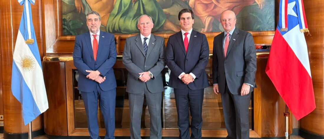 Cuatro representantes institucionales posan entre las banderas de Argentina y Chile durante una reunión vinculada al acuerdo para impulsar nuevos proyectos mineros.