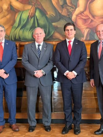 Cuatro representantes institucionales posan entre las banderas de Argentina y Chile durante una reunión vinculada al acuerdo para impulsar nuevos proyectos mineros.