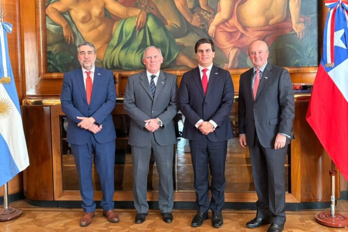 Cuatro representantes institucionales posan entre las banderas de Argentina y Chile durante una reunión vinculada al acuerdo para impulsar nuevos proyectos mineros.