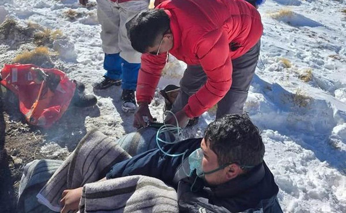 Personal de asistencia coloca oxígeno a un trabajador recostado sobre la nieve, en el contexto de Río Tinto bajo investigación por el accidente de los mineros de Fénix varados en la nieve.