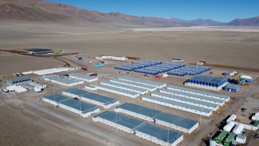 Vista aérea de un campamento minero de alta montaña, con módulos habitacionales e instalaciones operativas para el desarrollo de un proyecto de litio en la Puna argentina.