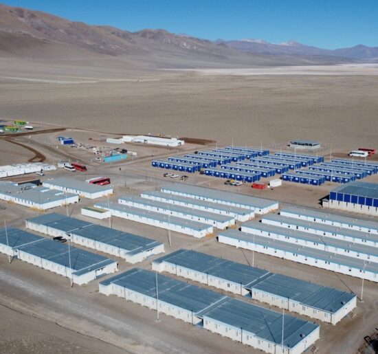 Vista aérea de un campamento minero de alta montaña, con módulos habitacionales e instalaciones operativas para el desarrollo de un proyecto de litio en la Puna argentina.