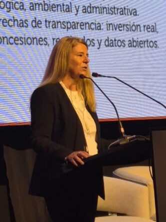 Una expositora en el escenario de Argentina Mining 2026 frente a una pantalla sobre indicadores y transparencia para la exploración minera en Salta y Jujuy.